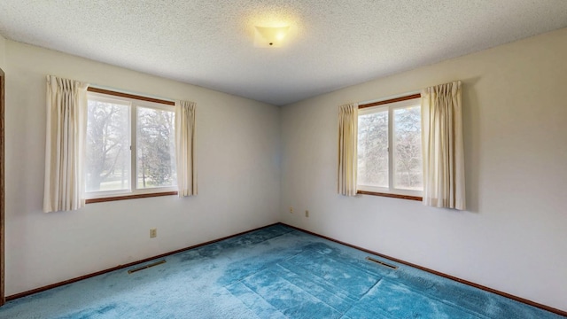 unfurnished room with carpet flooring, a textured ceiling, and baseboards