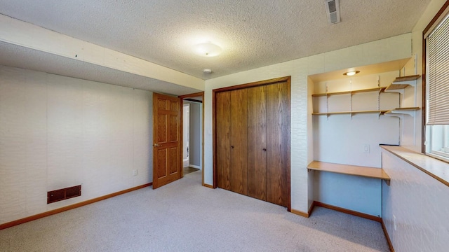 unfurnished bedroom with a closet, a textured ceiling, baseboards, and carpet floors