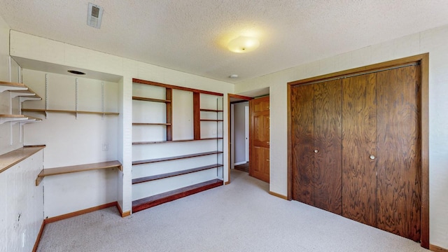 unfurnished bedroom featuring carpet flooring, a textured ceiling, baseboards, and a closet