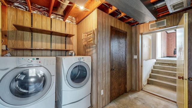 laundry area with washer and clothes dryer and wooden walls