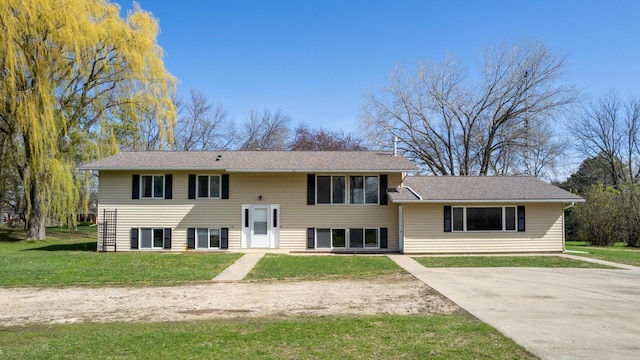 view of front of property featuring a front lawn, driveway, and roof with shingles
