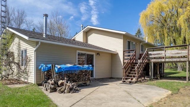 rear view of property with stairway, a deck, a patio area, and a shingled roof