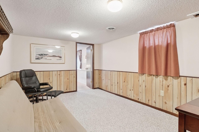 sitting room featuring wooden walls, a wainscoted wall, and a textured ceiling