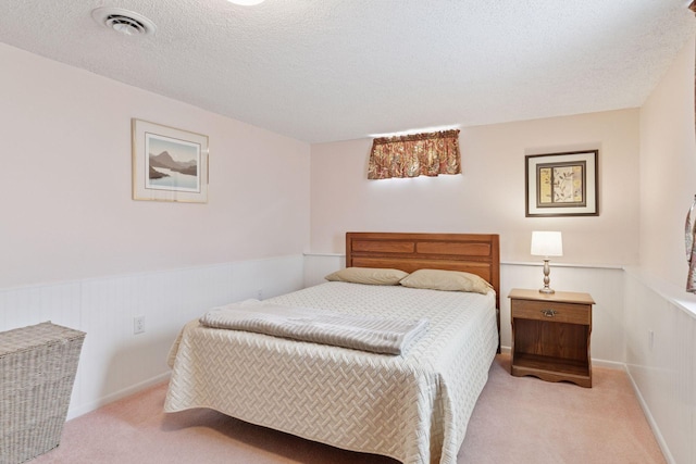 carpeted bedroom featuring a textured ceiling, a wainscoted wall, and baseboards