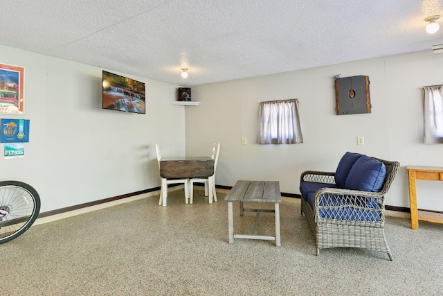 sitting room with a textured ceiling, baseboards, and speckled floor