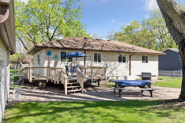 back of property featuring a deck, roof with shingles, and a patio