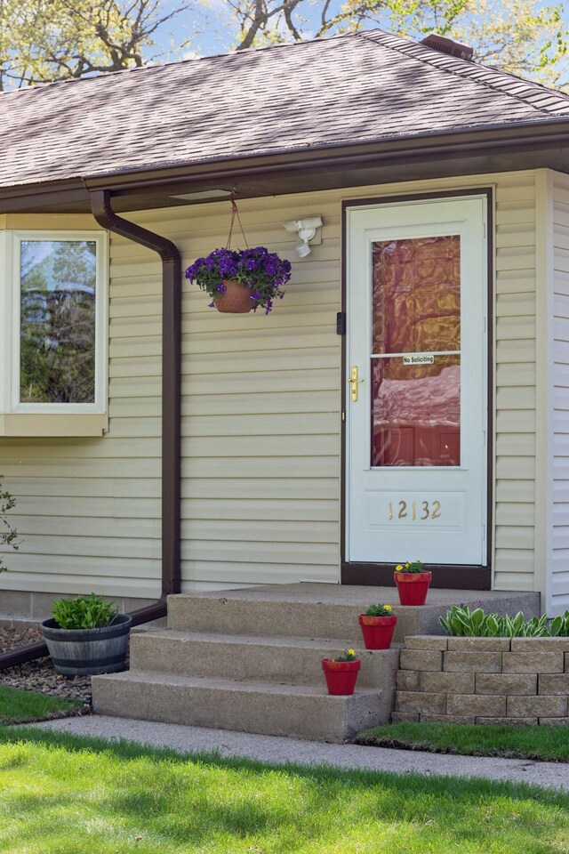 entrance to property featuring roof with shingles
