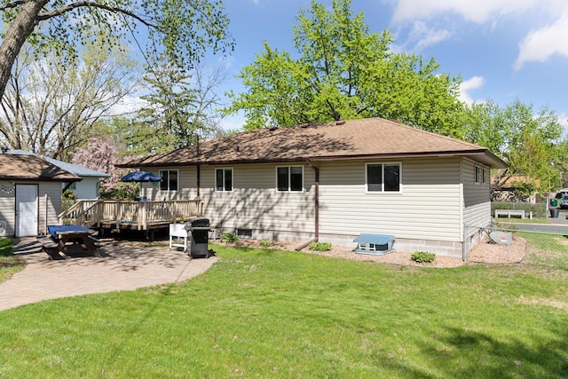 rear view of property featuring a wooden deck, a lawn, and a patio area
