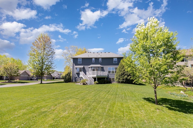 rear view of house featuring stairs, a lawn, and a deck