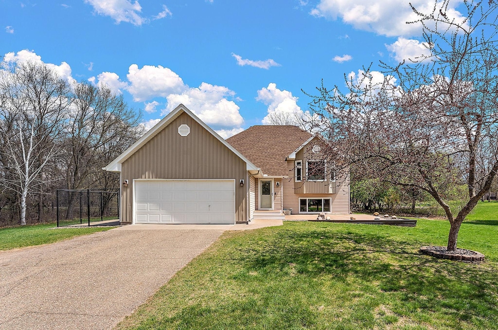 24271 Amazon St NE, Stacy, MN 55079 - tri-level home featuring fence, a front lawn, a garage, board and batten siding, and driveway