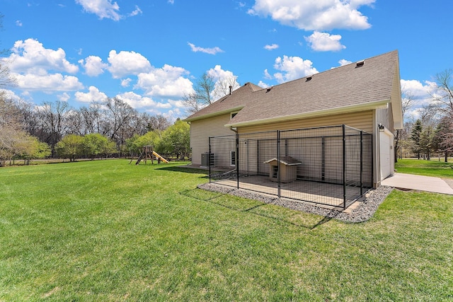 back of house with a lawn, central AC unit, and a playground
