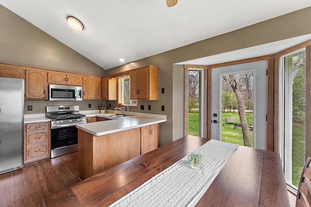 kitchen with a sink, light countertops, a peninsula, stainless steel appliances, and dark wood-type flooring