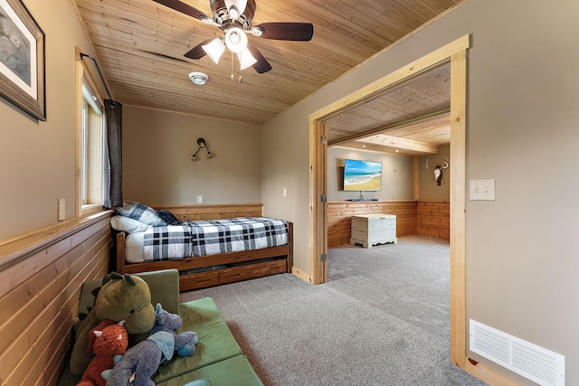 carpeted bedroom with visible vents, wainscoting, and wooden ceiling