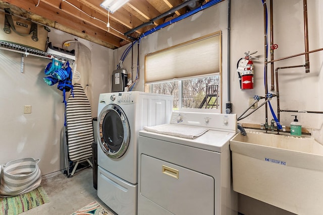 clothes washing area with washer and clothes dryer and a sink