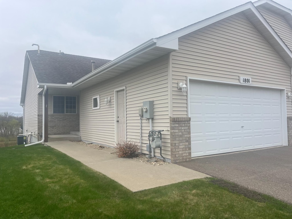 view of property exterior with brick siding, aphalt driveway, roof with shingles, and a garage