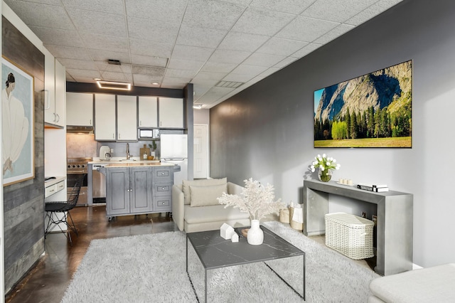 living room featuring concrete floors and a drop ceiling