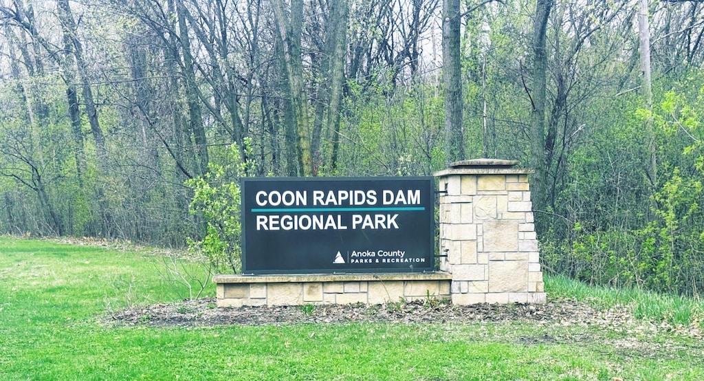 community / neighborhood sign featuring a wooded view