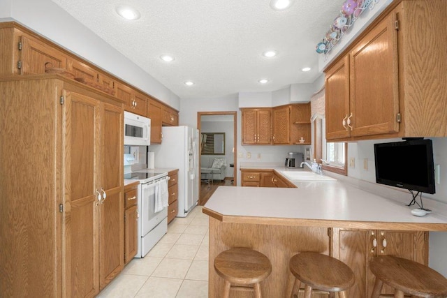 9967 Egret Blvd NW, Coon Rapids, MN 55433 - kitchen with white appliances, a peninsula, a breakfast bar area, light countertops, and a textured ceiling