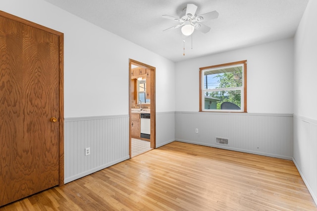 3618 1st St NW, Rochester, MN 55901 - unfurnished bedroom with a wainscoted wall, light wood-style flooring, ensuite bath, and ceiling fan