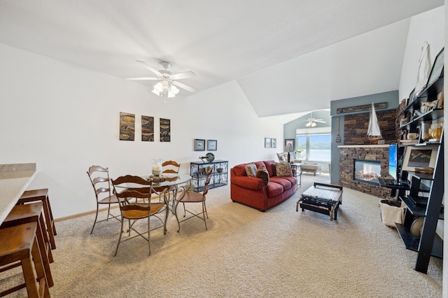 dining area with ceiling fan, carpet flooring, a stone fireplace, vaulted ceiling, and baseboards