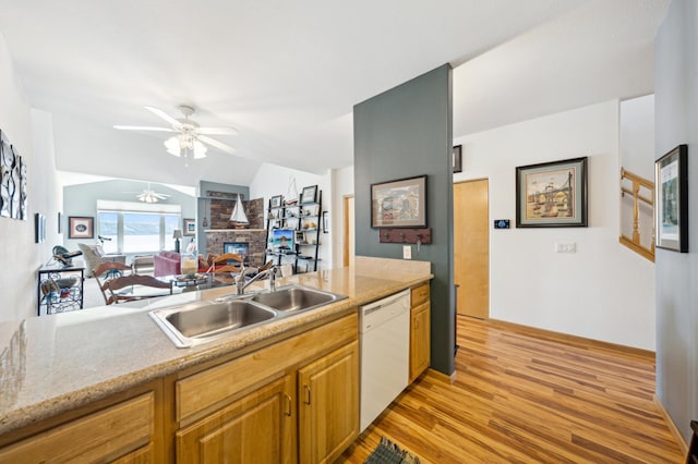 kitchen featuring dishwasher, a sink, a ceiling fan, a fireplace, and light wood-style flooring