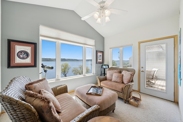 living room featuring vaulted ceiling, light colored carpet, a ceiling fan, and a water view