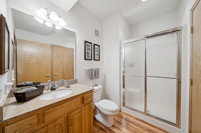 bathroom featuring a shower stall, toilet, wood finished floors, and vanity