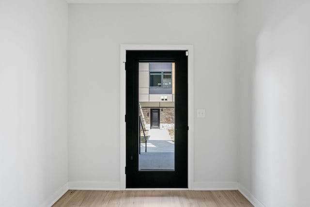 doorway featuring baseboards and light wood finished floors