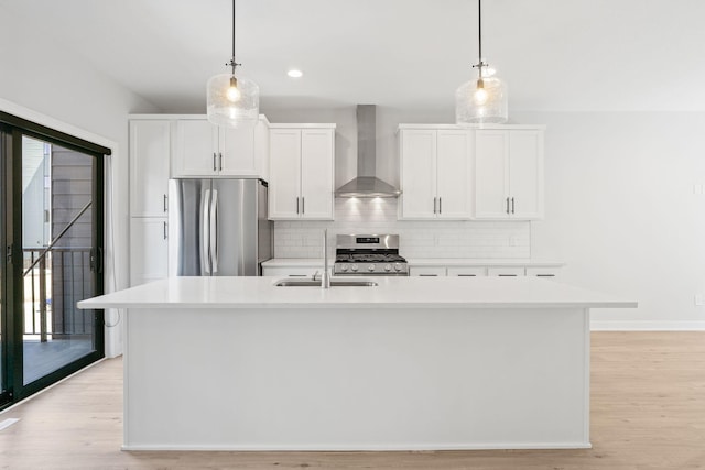 kitchen featuring wall chimney range hood, appliances with stainless steel finishes, a sink, light countertops, and tasteful backsplash