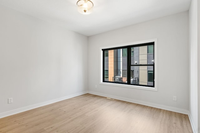 spare room with baseboards and light wood-type flooring