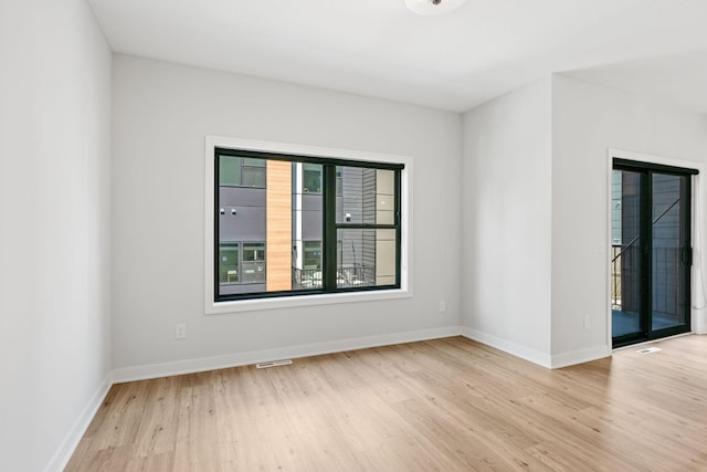 unfurnished room featuring baseboards, visible vents, and wood finished floors