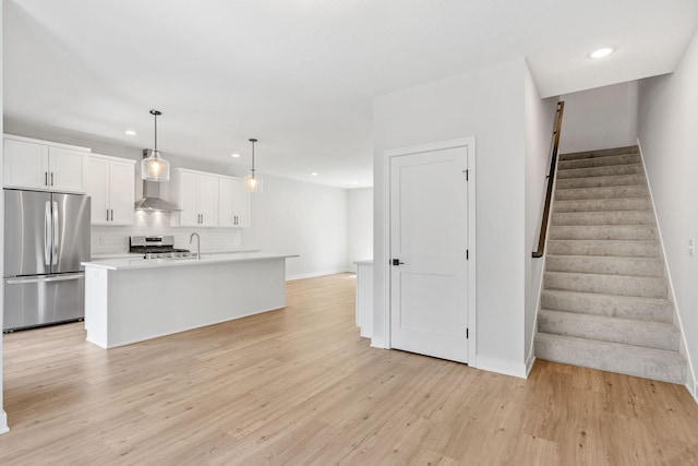 kitchen featuring recessed lighting, wall chimney exhaust hood, white cabinets, tasteful backsplash, and appliances with stainless steel finishes