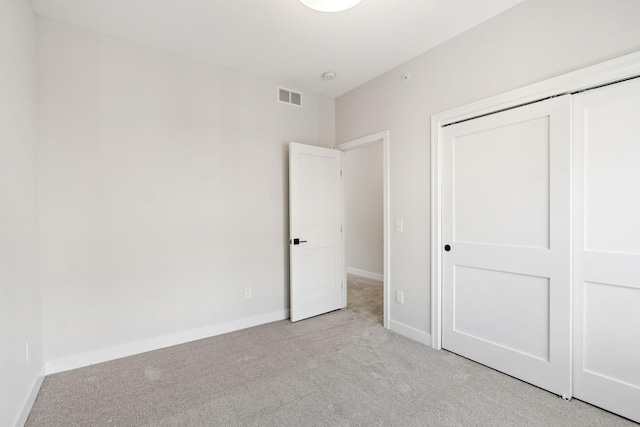 unfurnished bedroom featuring baseboards, visible vents, light carpet, and a closet