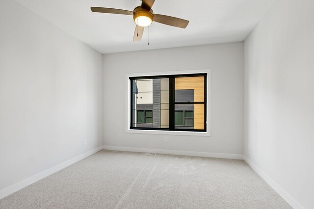 spare room featuring a ceiling fan, baseboards, and light carpet
