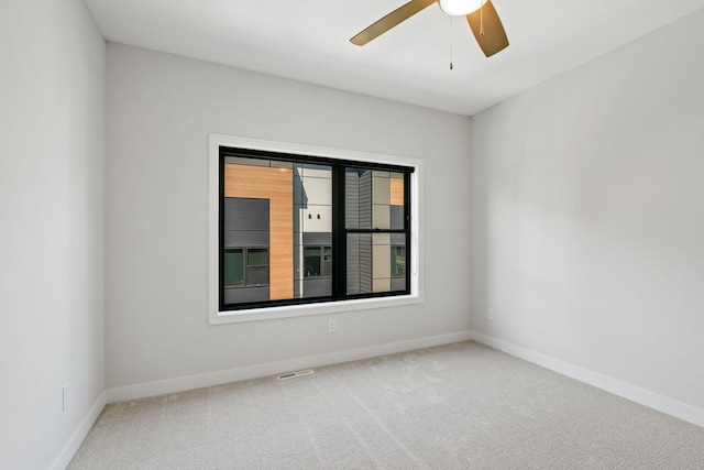 carpeted spare room with baseboards, visible vents, and ceiling fan