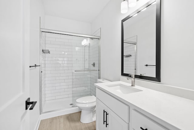 bathroom featuring vanity, wood finished floors, toilet, and a shower stall