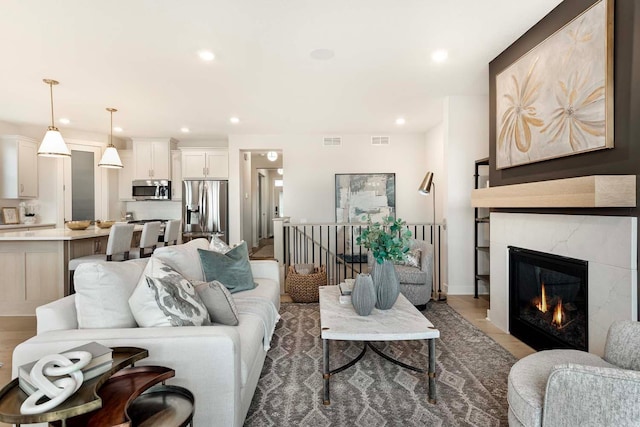 living area with a high end fireplace, recessed lighting, and visible vents