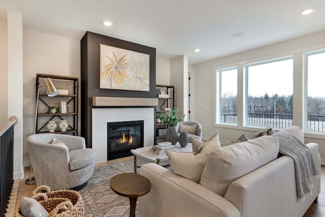living area with recessed lighting, a high end fireplace, baseboards, and wood finished floors