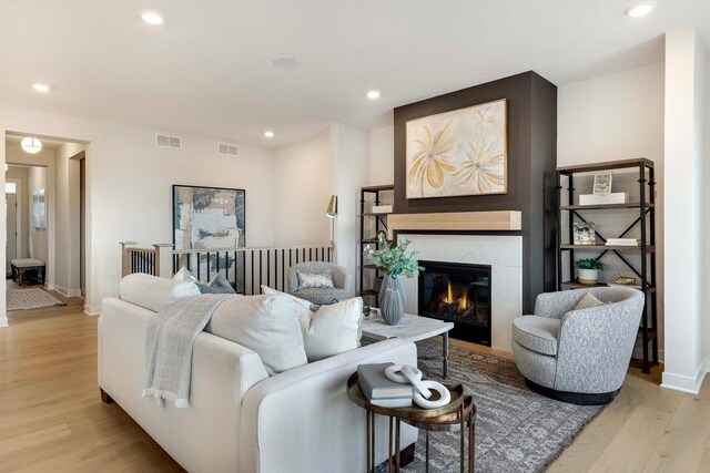living area with a high end fireplace, recessed lighting, light wood finished floors, and visible vents