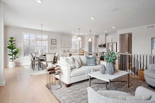 living room featuring recessed lighting, visible vents, an inviting chandelier, and light wood-style floors