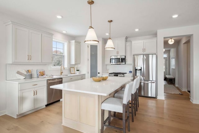 kitchen featuring decorative backsplash, a kitchen island, light countertops, white cabinetry, and stainless steel appliances