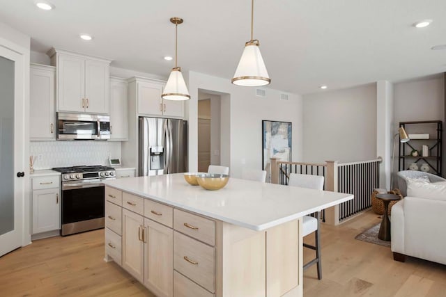 kitchen featuring a breakfast bar, light wood-style floors, a center island, stainless steel appliances, and tasteful backsplash