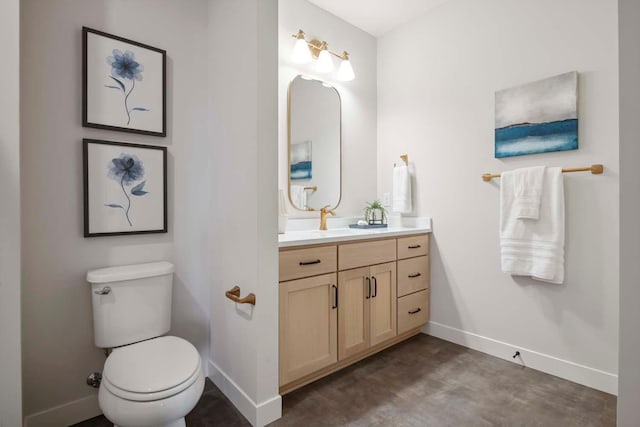 bathroom featuring baseboards, vanity, and toilet