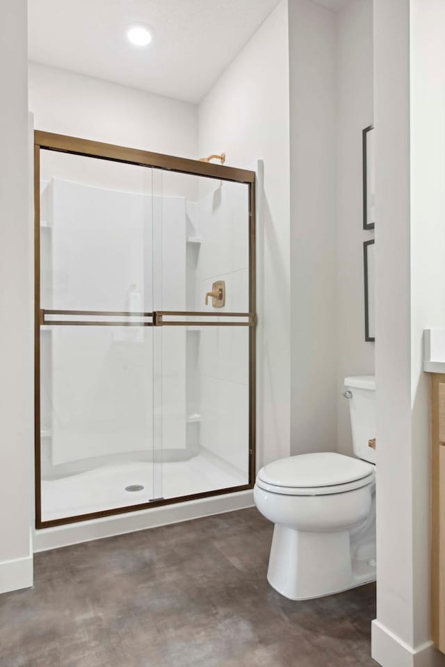 bathroom with toilet, concrete flooring, and a shower stall