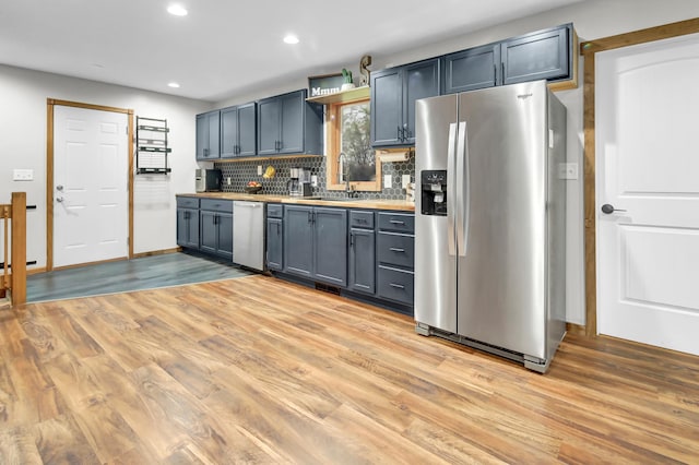 kitchen with appliances with stainless steel finishes, a sink, and light wood-style floors