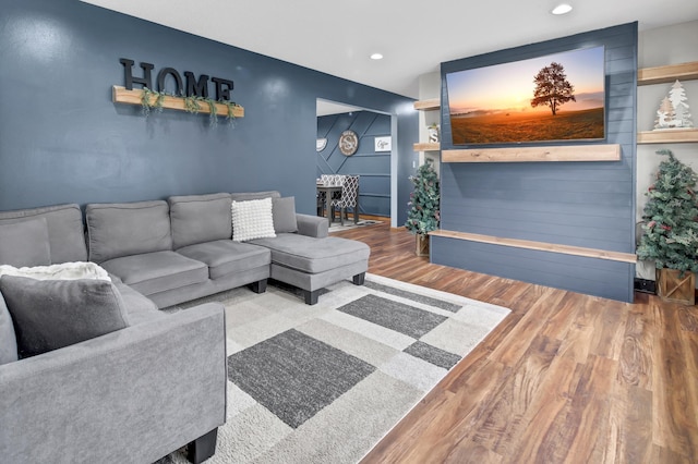 living room with baseboards, an accent wall, recessed lighting, and wood finished floors