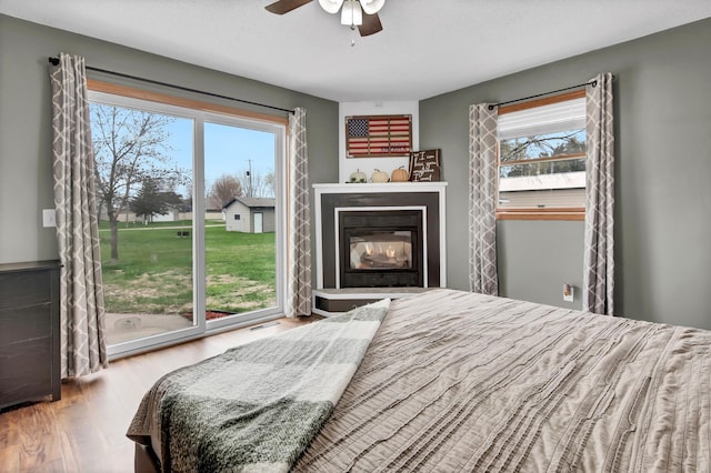 bedroom featuring a ceiling fan, visible vents, multiple windows, and wood finished floors