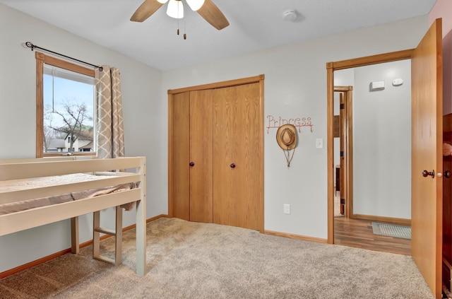 carpeted bedroom with a ceiling fan, baseboards, and a closet