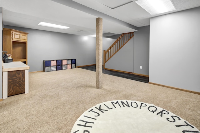 finished basement with carpet floors, baseboards, and a drop ceiling
