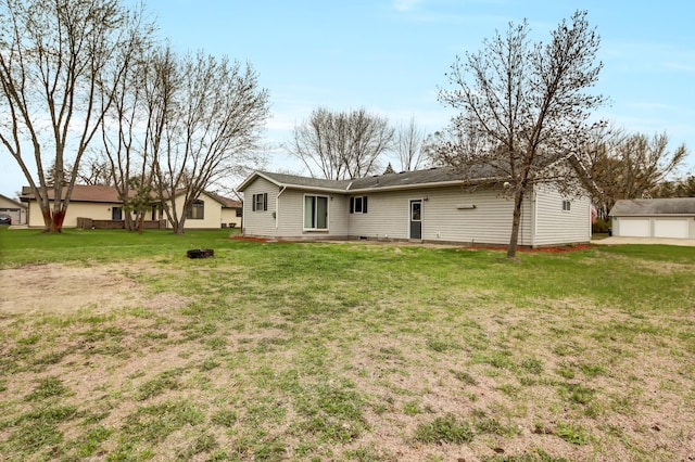 rear view of house featuring a lawn, an outdoor structure, and a detached garage